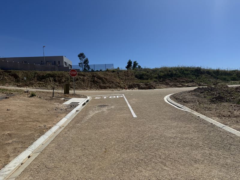 Paved road junction with a painted STOP line and a stop sign, bare ground on both sides
